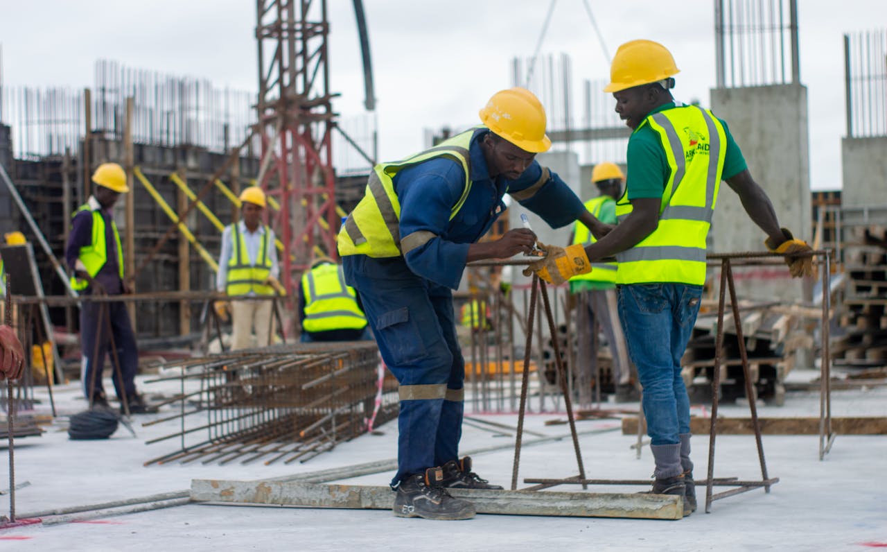 journey A diverse group of construction workers in safety gear at an active building site.